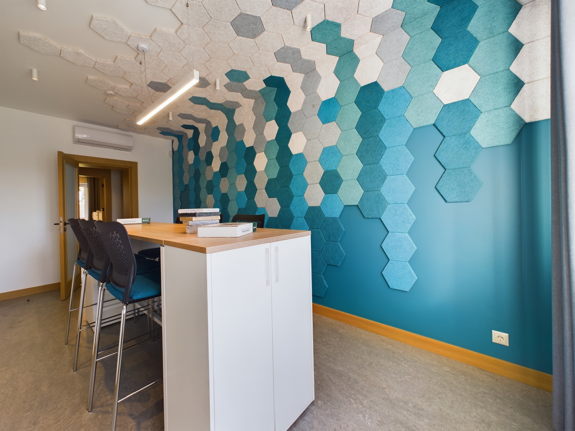 Moderna biroja virtuves/bāra zona ar sešstūra formas akustiskajiem paneļiem un augstiem krēsliem. Kvalitatīva komercplatību fotogrāfija Rīgā.