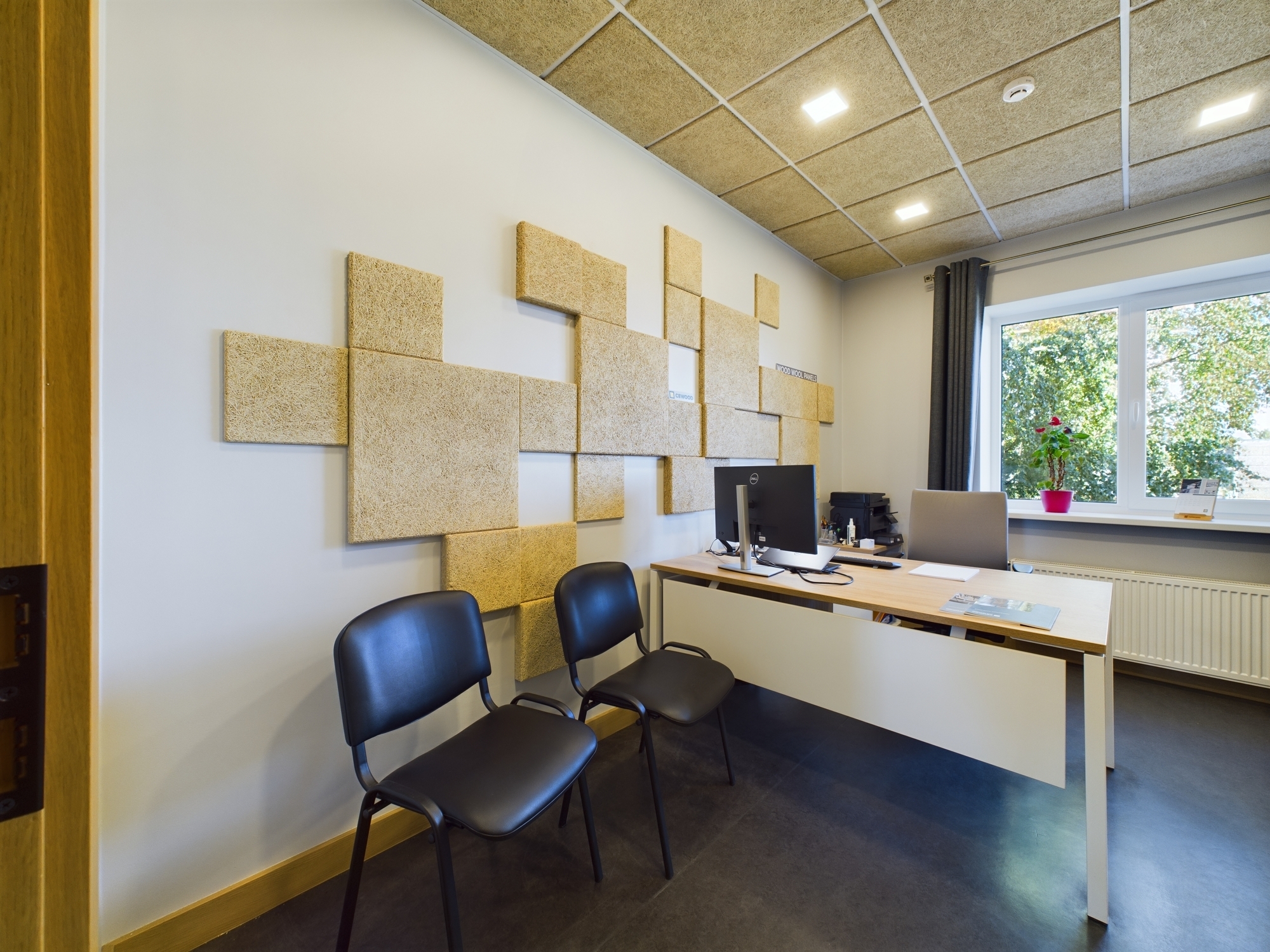 Biroja telpa ar radošu akustisko paneļu sienu, darba galdu un krēsliem. Kvalitatīva komercplatību fotogrāfija Rīgā.