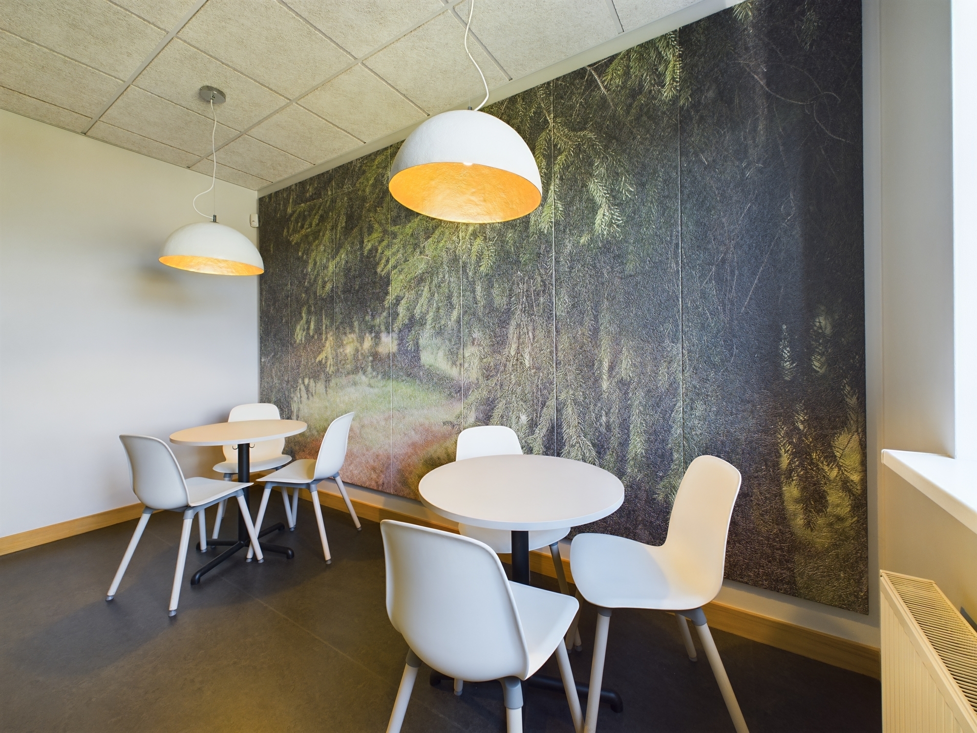 Mūsdienīga biroja telpa ar baltiem galdiņiem, krēsliem un dizaina sienas apdari. Kvalitatīva komercplatību fotogrāfija Rīgā.