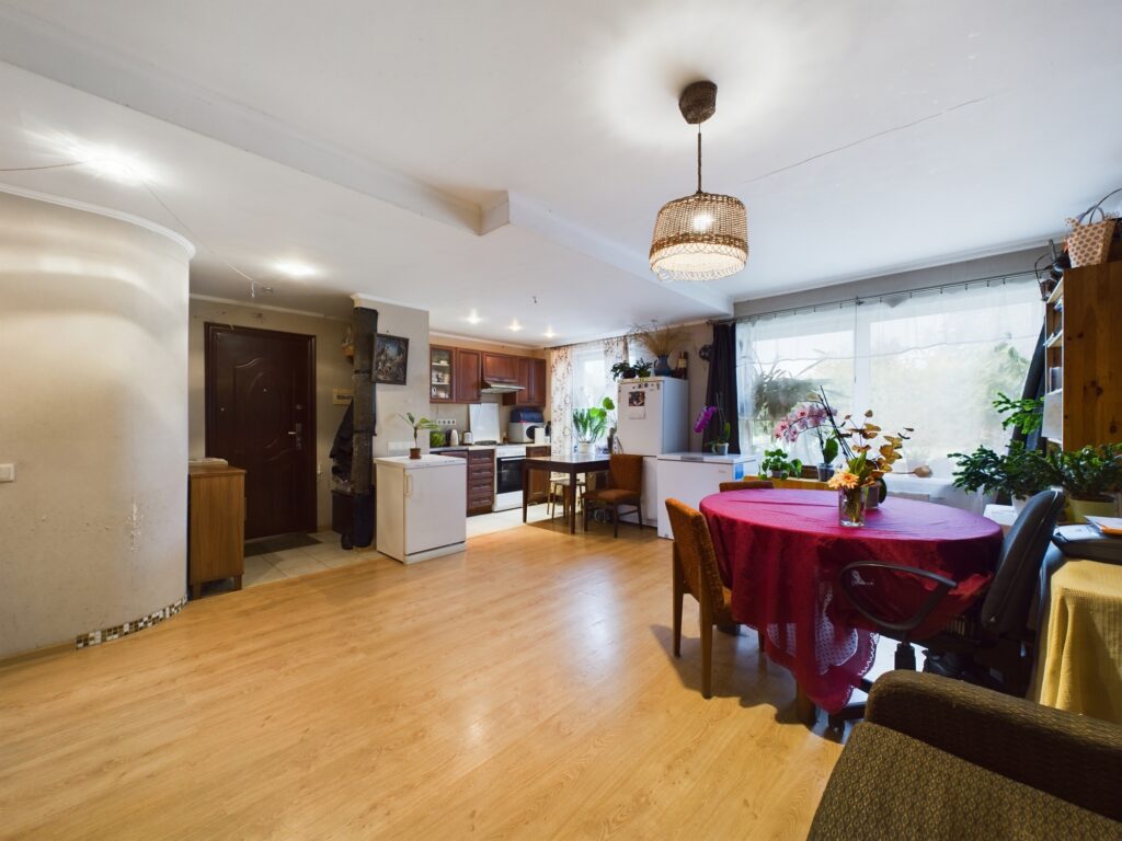 Atvērta plānojuma telpa ar virtuves zonu un ēdamgaldu. Kvalitatīva nekustamā īpašuma fotogrāfija Zvejniekciemā.