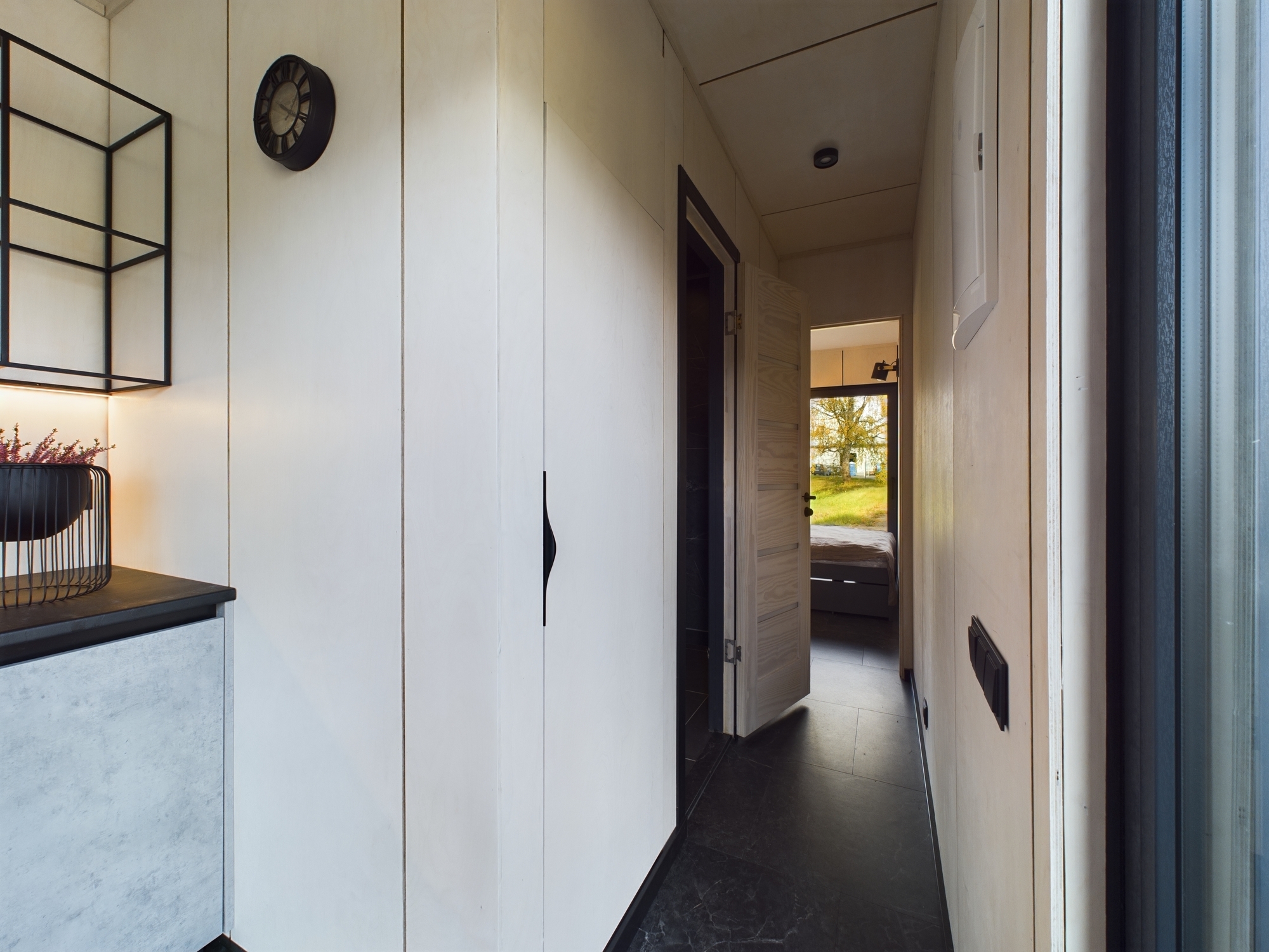 Funkcionāls priekšnams ar baltiem iebūvētiem skapjiem un durvīm. Perspekīvs kadrs, kas demonstrē telpas plūsmu. Kvalitatīva nekustamā īpašuma fotogrāfija.