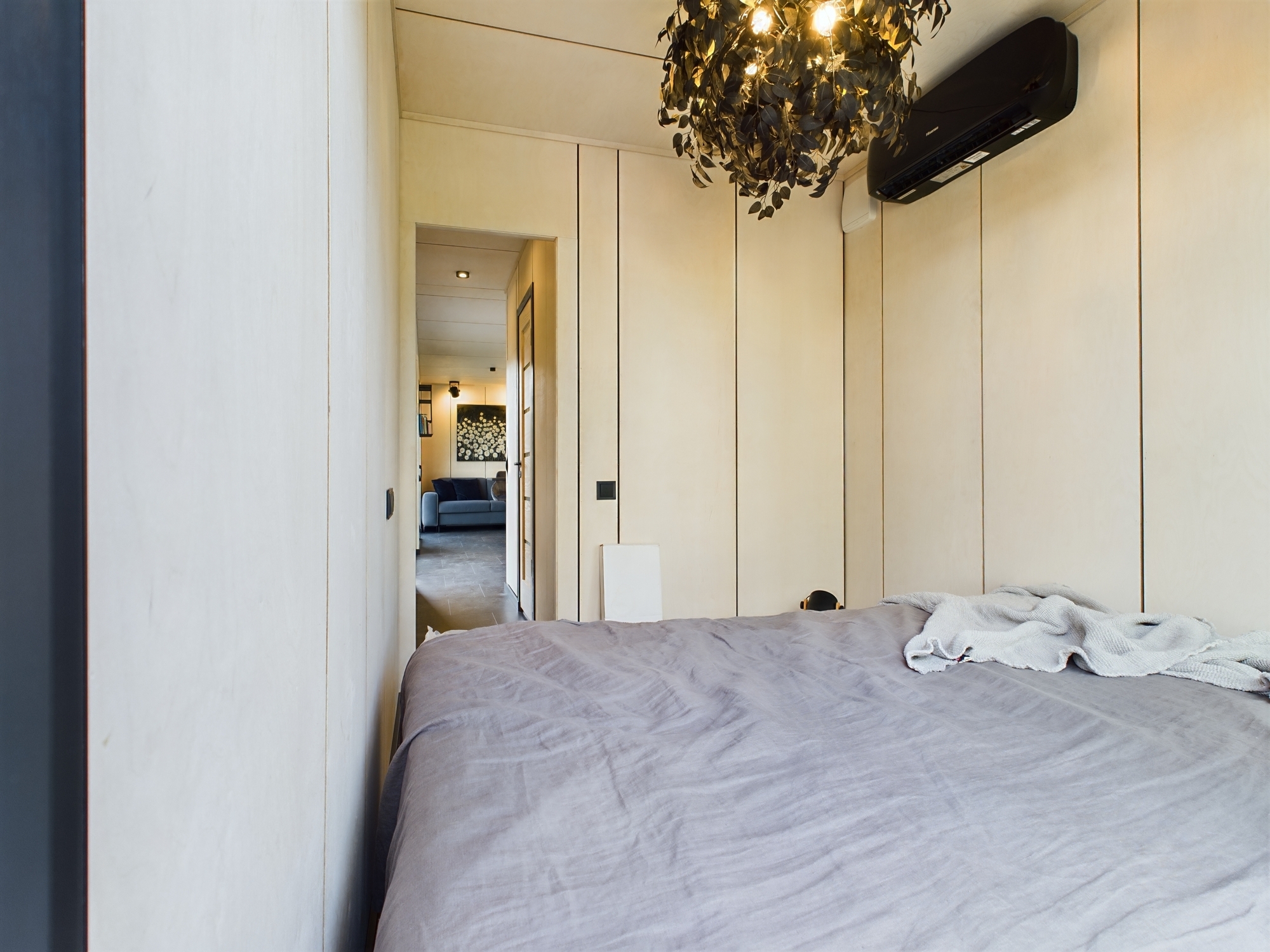 Mājīga guļamistaba ar koka sienu apdari, gultu un gaisa kondicionieri. Kvalitatīva nekustamā īpašuma fotogrāfija.