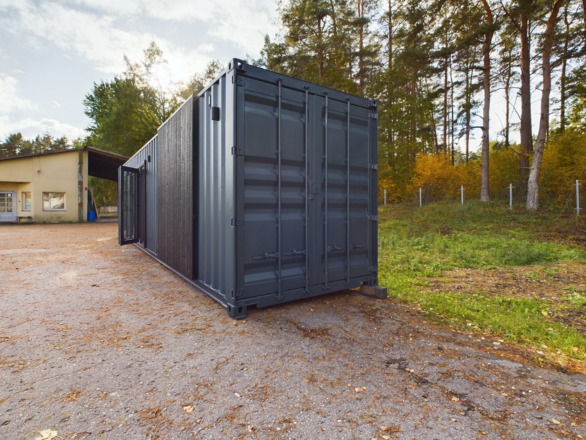 Tumši pelēks konteinera tipa modulis būvniecības sākumposmā. Kvalitatīva saliekamo māju projektu fotogrāfija.