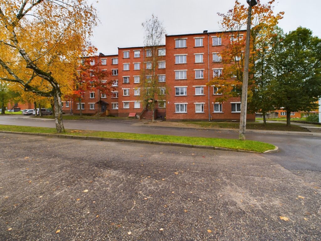 Ēkas fasāde Liepājā ar rudens krāsās nokrāsotiem kokiem. Tipiska daudzdzīvokļu māja pārdošanai