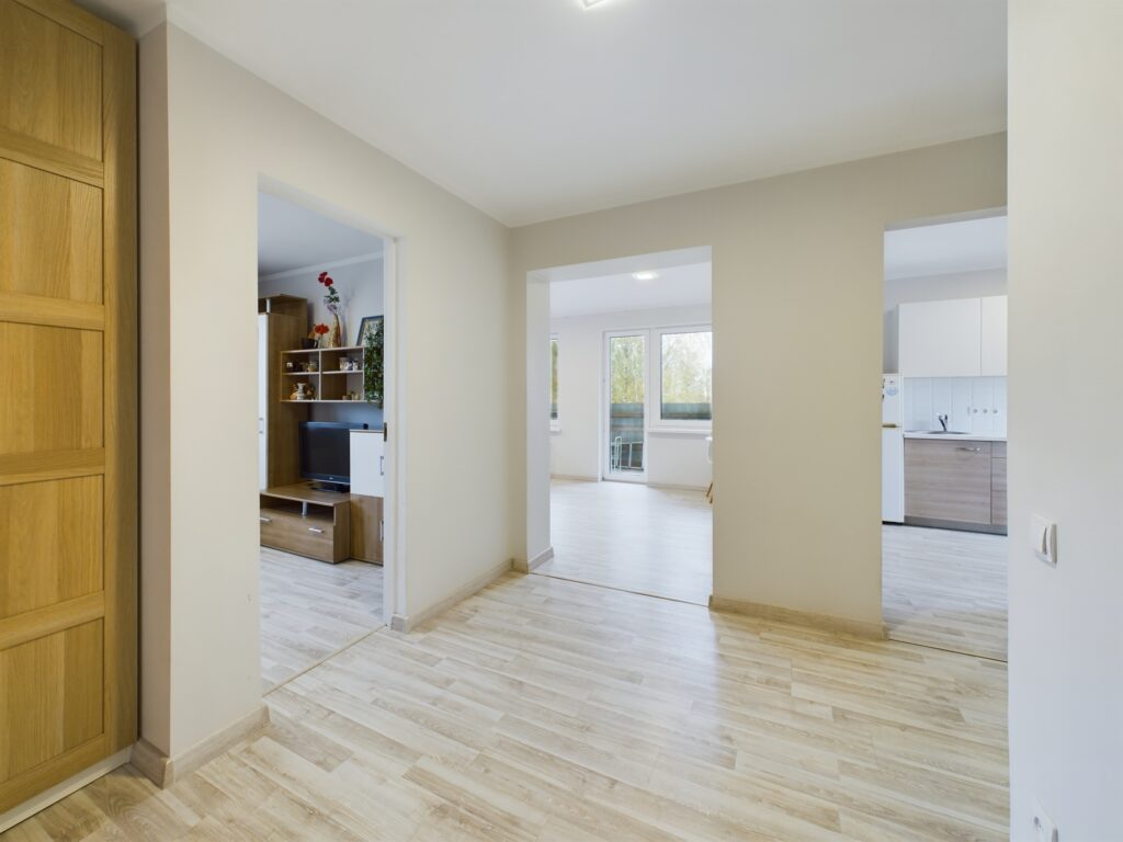 Plašs un gaišs dzīvokļa priekšnams ar koka lamināta grīdu un iebūvētu uzglabāšanas sistēmu. Kvalitatīva nekustamā īpašuma fotogrāfija Siguldā.