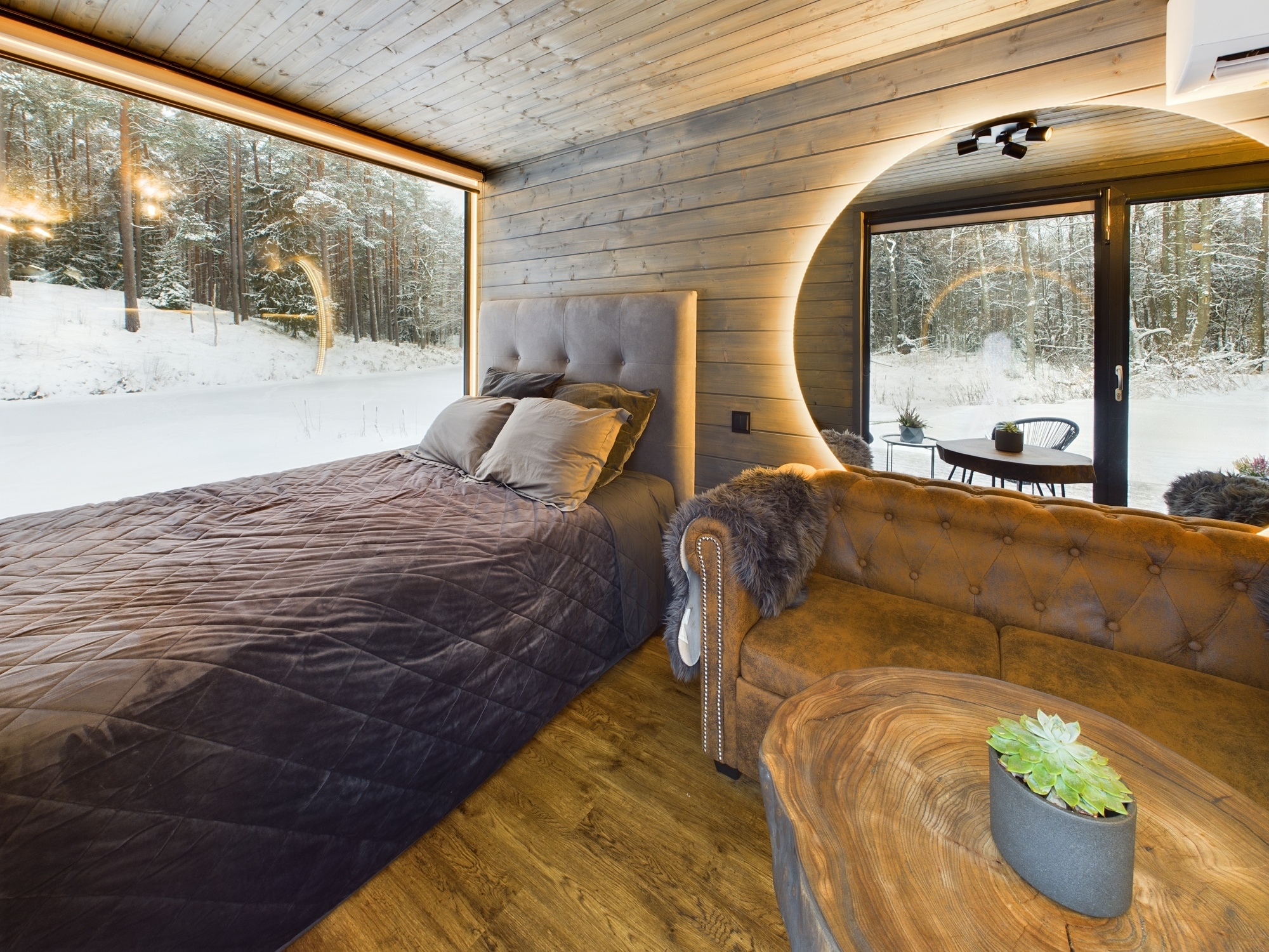 Ekskluzīva guļamistaba ar panorāmas logu, kas sniedz skatu uz dabu. Unikāls dizains koka interjerā. Kvalitatīva nekustamā īpašuma fotogrāfija.