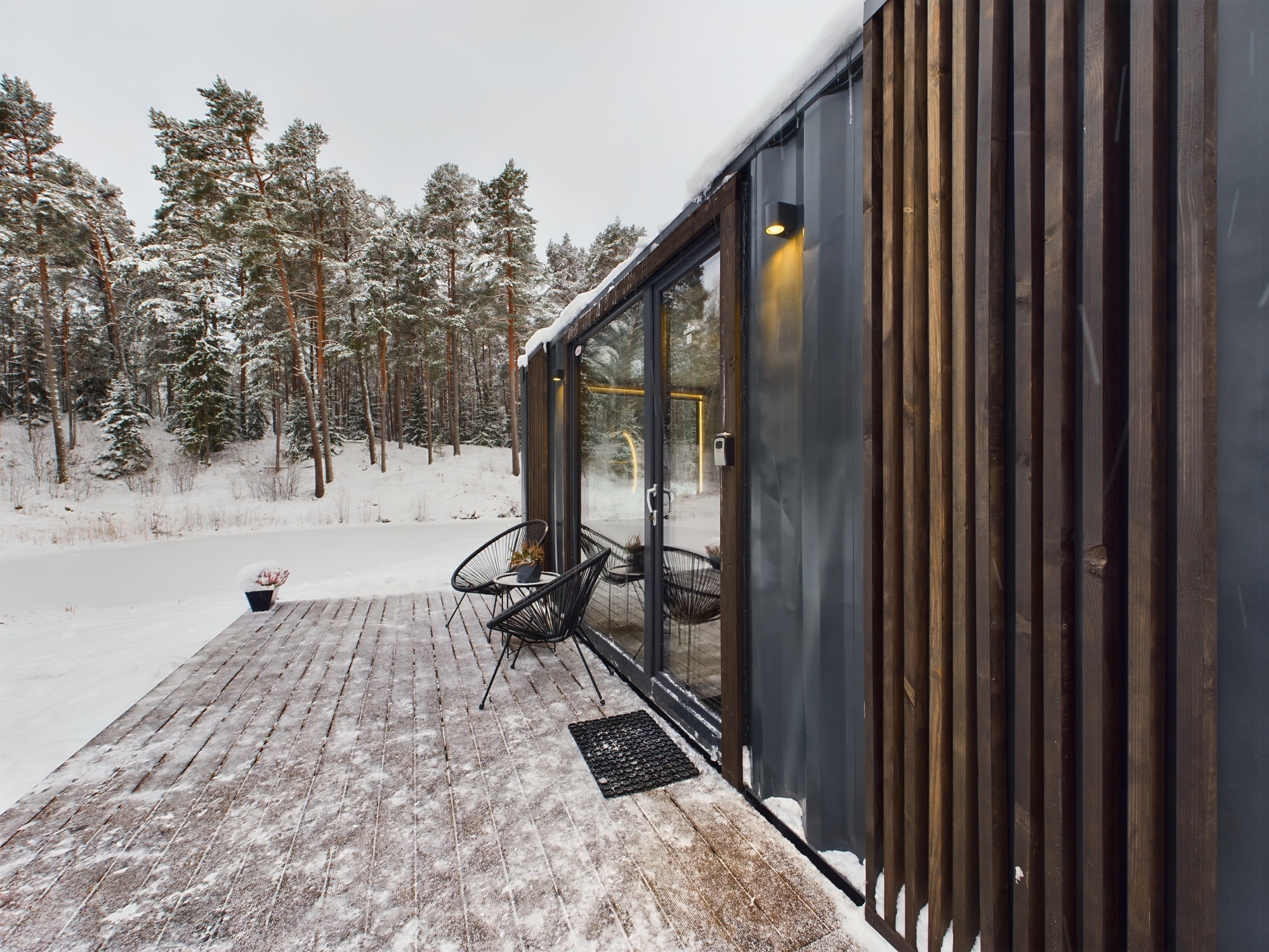 Detalizēts kadrs: Vertikāla koka apdare un lieli stikla logi uz terases. Kvalitatīva moduļu mājas fasādes fotogrāfija.