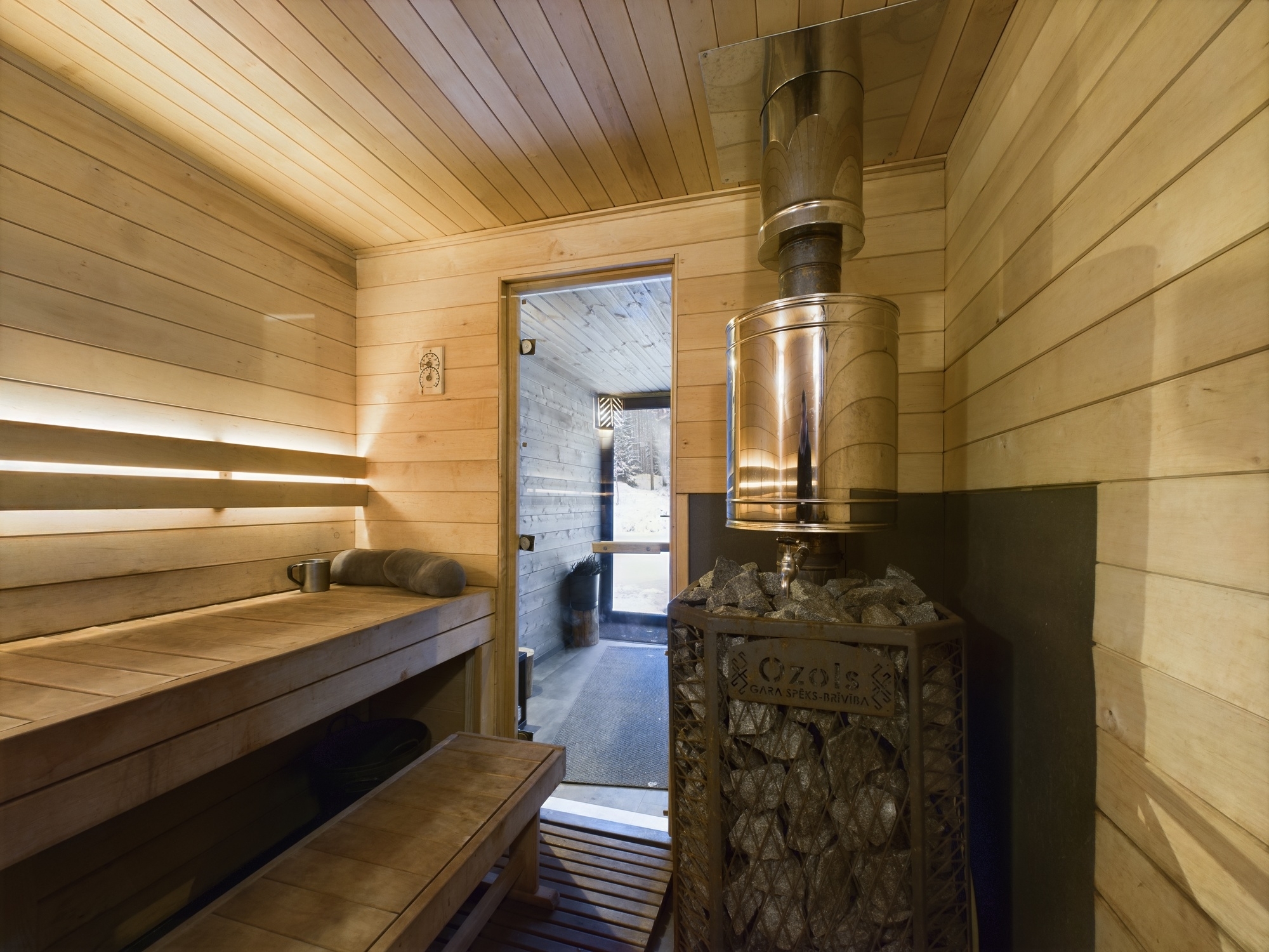 Tradicionāla pirts telpa ar koka apdari, lāvām un metāla malkas krāsni. Kvalitatīva nekustamā īpašuma fotogrāfija.