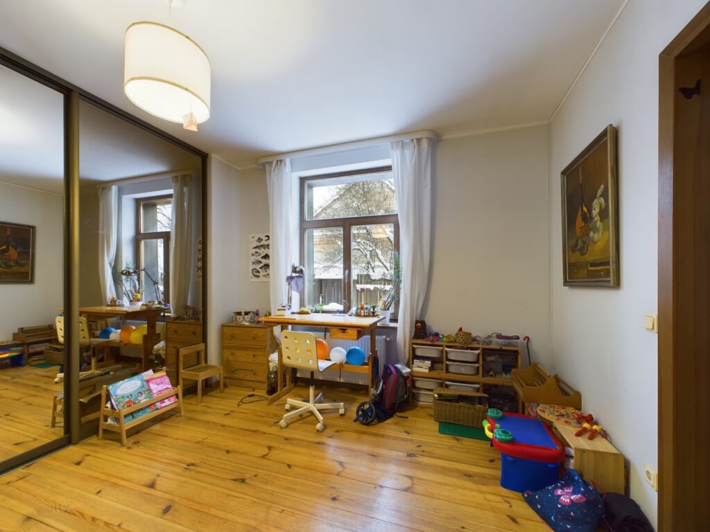Plaša guļamistaba ar iebūvētu spoguļskapi un koka grīdu. Kvalitatīva dzīvokļa fotogrāfija Rīgas Imantas rajonā.