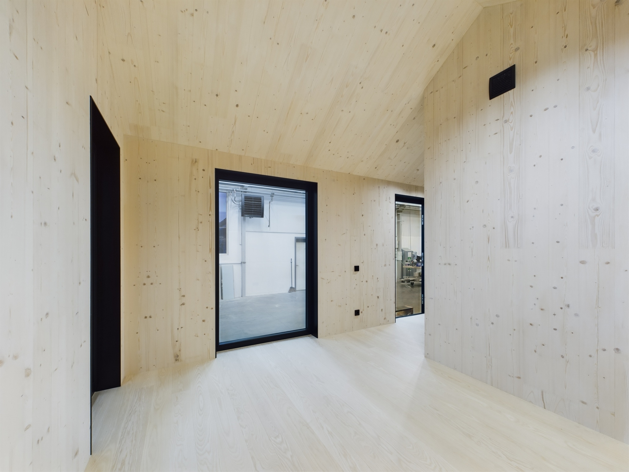 Tīra, tukša moduļu mājas telpa ar gaišu koka apdari uz sienām un griestiem. Kvalitatīva arhitektūras fotogrāfija.