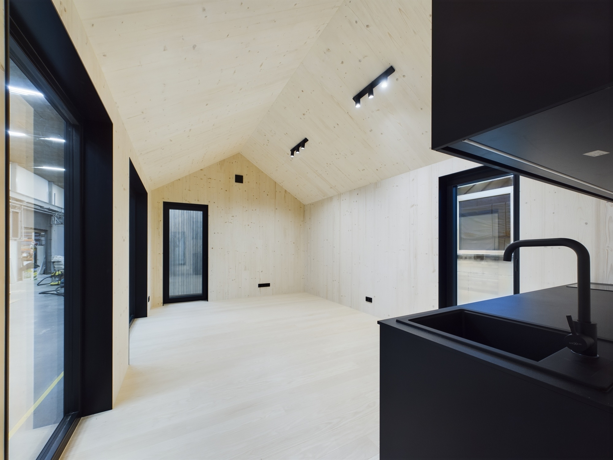 Augstas klases mansarda virtuve skandināvu stilā ar melnu virtuves salu un koka sienām. Nekustamā īpašuma pārdošana.