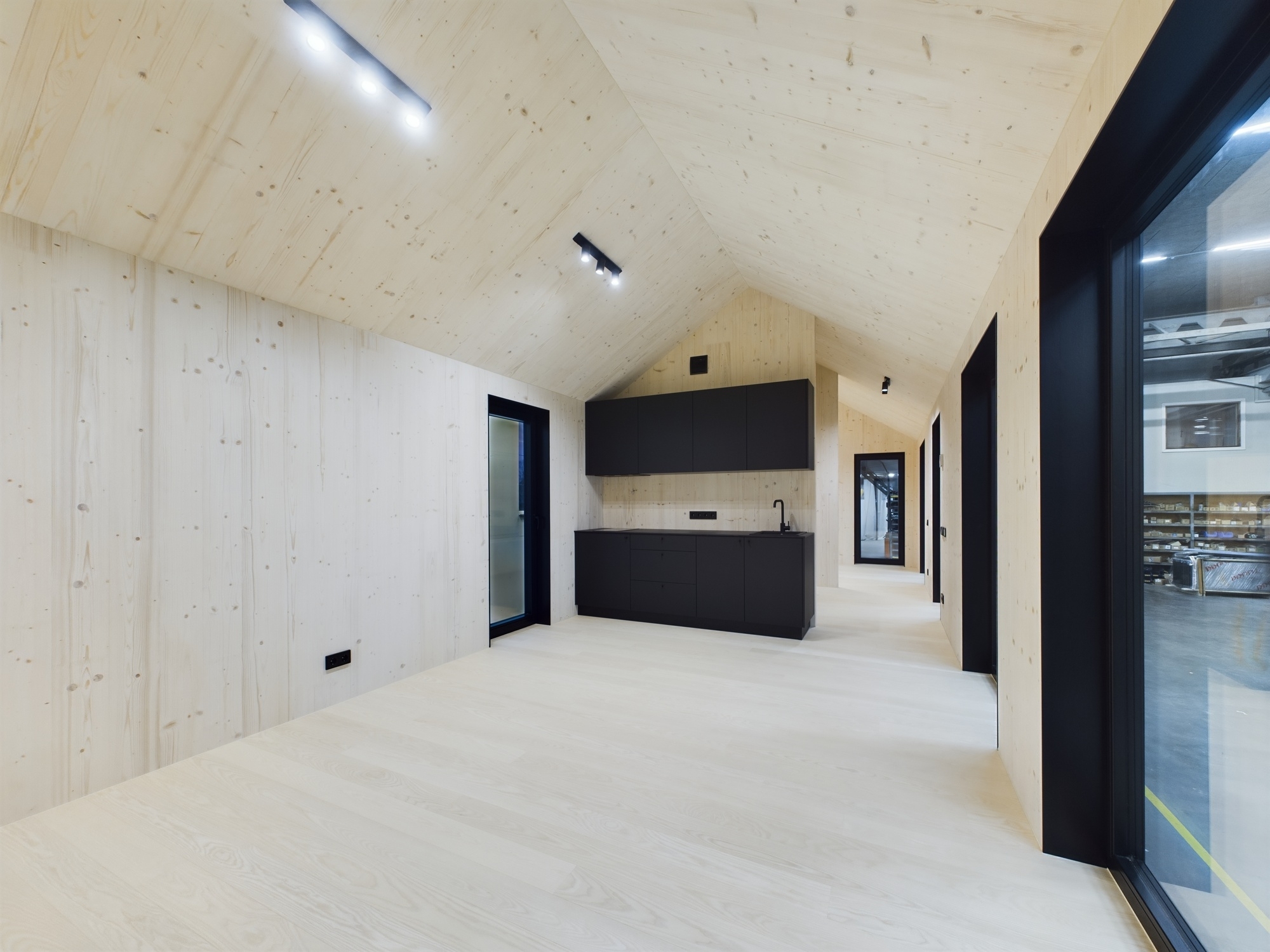 Tīras līnijas un augsti griesti. Tukša moduļu mājas telpa ar gaišu koka apdari un lieliem logiem. Kvalitatīva fotogrāfija.