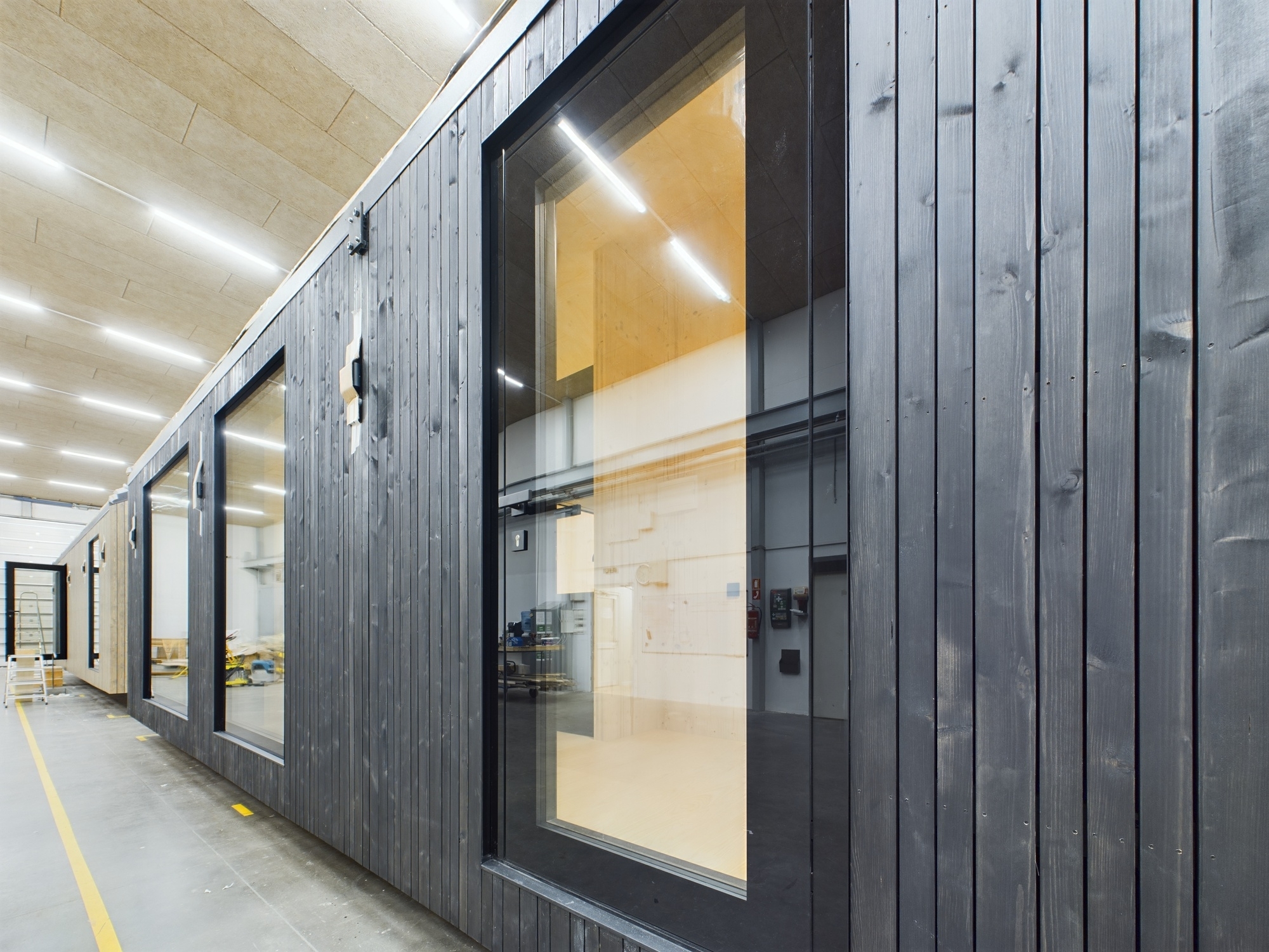 Tuvplāns: Melnas koka apdares un logu detaļas uz moduļu mājas fasādes (Nordicable projekts). Kvalitatīva būvniecības fotogrāfija.