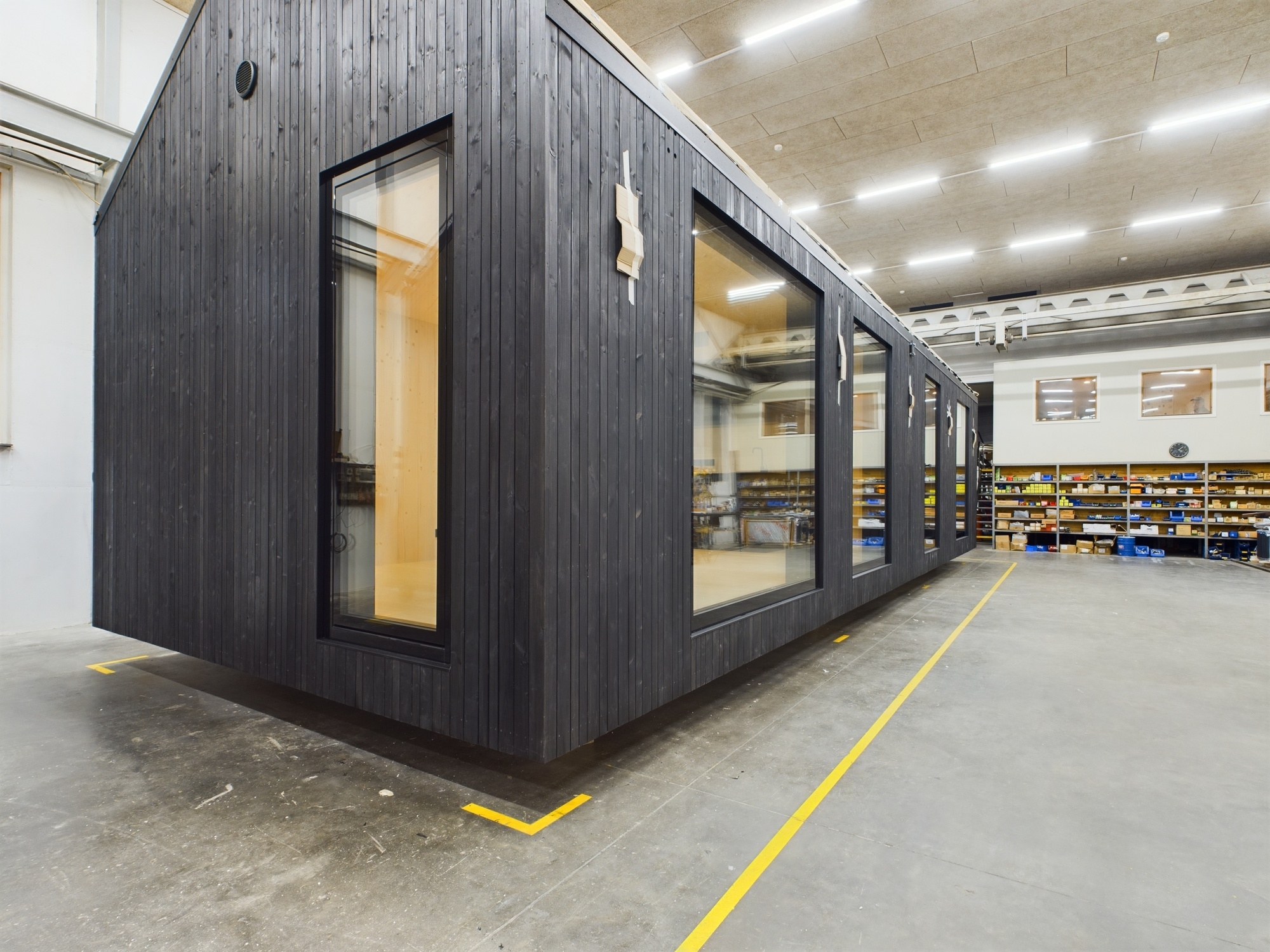 Mūsdienīga, melna moduļu māja (tiny house) būvniecības procesā. Kvalitatīva saliekamo māju projektu fotogrāfija.