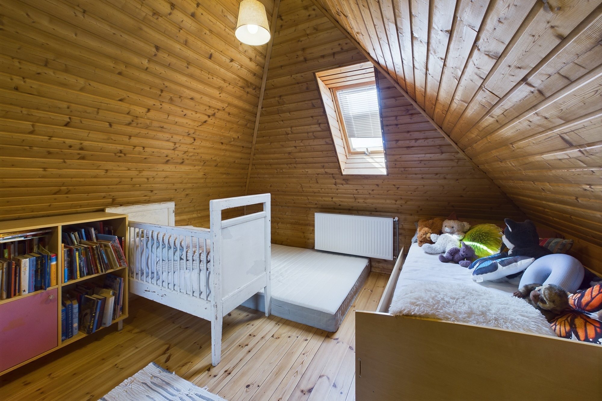 Mājīga mansarda telpa ar koka apdari, jumta logu un gultām. Kvalitatīva interjera fotogrāfija ģimenei.