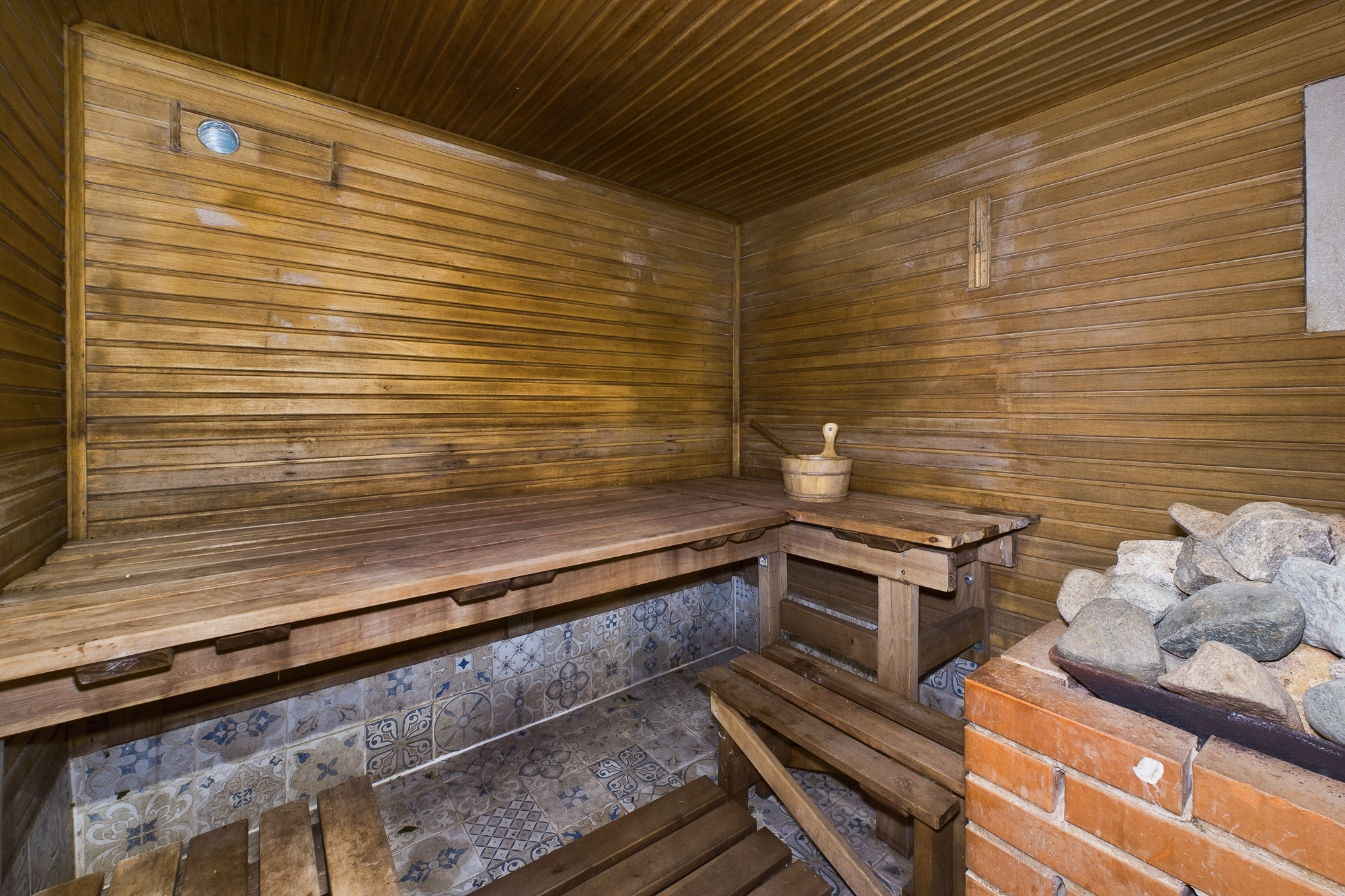 Pirts telpa ar koka lāvu un akmeņu krāsni. Kvalitatīva labsajūtas zonas interjera fotogrāfija.