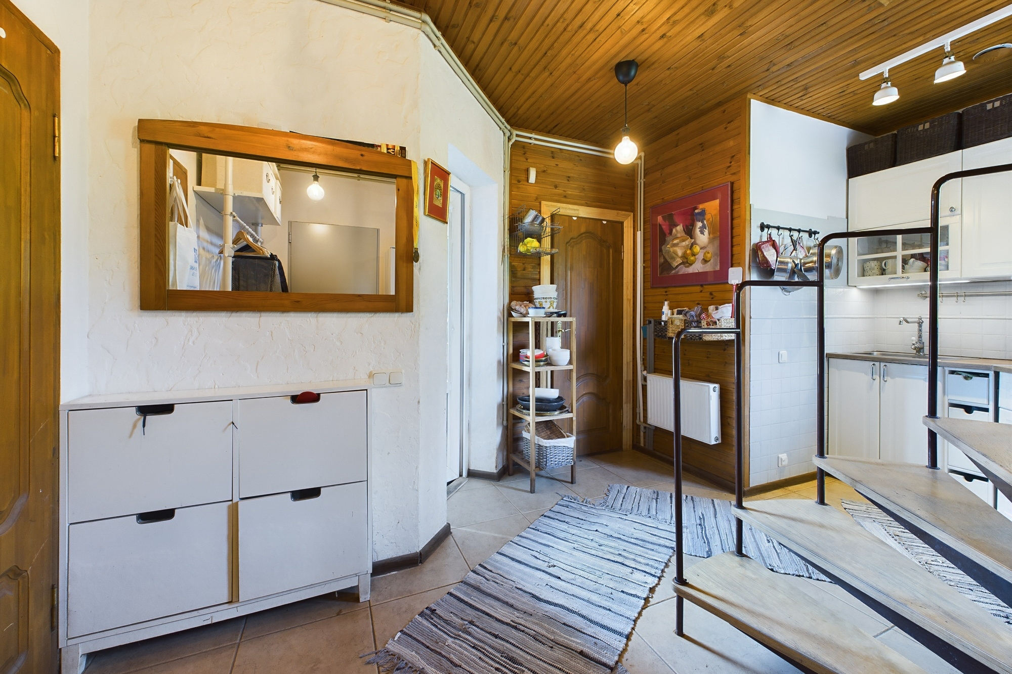 Funkcionāla telpa ar nelielu virtuves zonu un ieejas mēbelēm. Kvalitatīva interjera fotogrāfija.