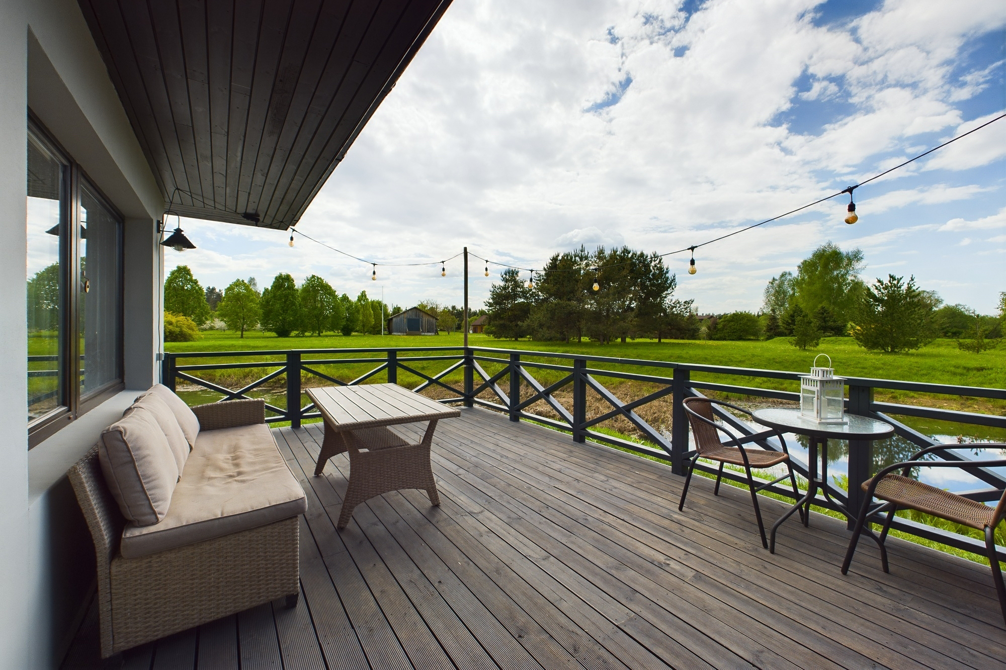 Koka terase ar mīkstām mēbelēm, kas savienojas ar mājas fasādi. Nekustamā īpašuma pārdošana.