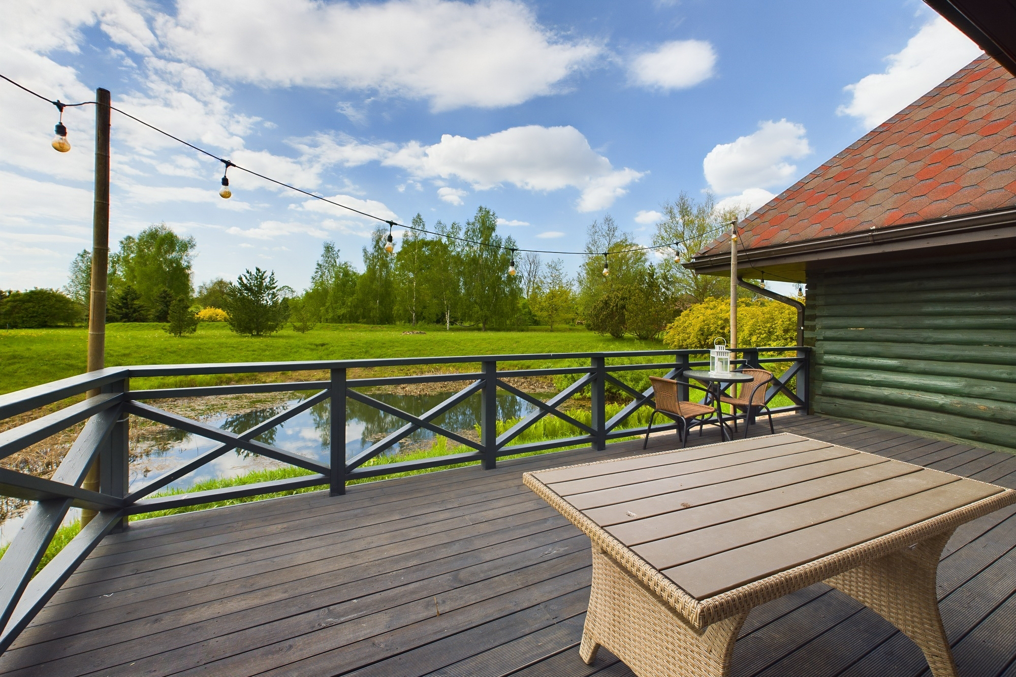 Labiekārtota koka terase pie privātmājas ar āra mēbelēm un skatu. Īpašumu pārdošana Pierīgā.