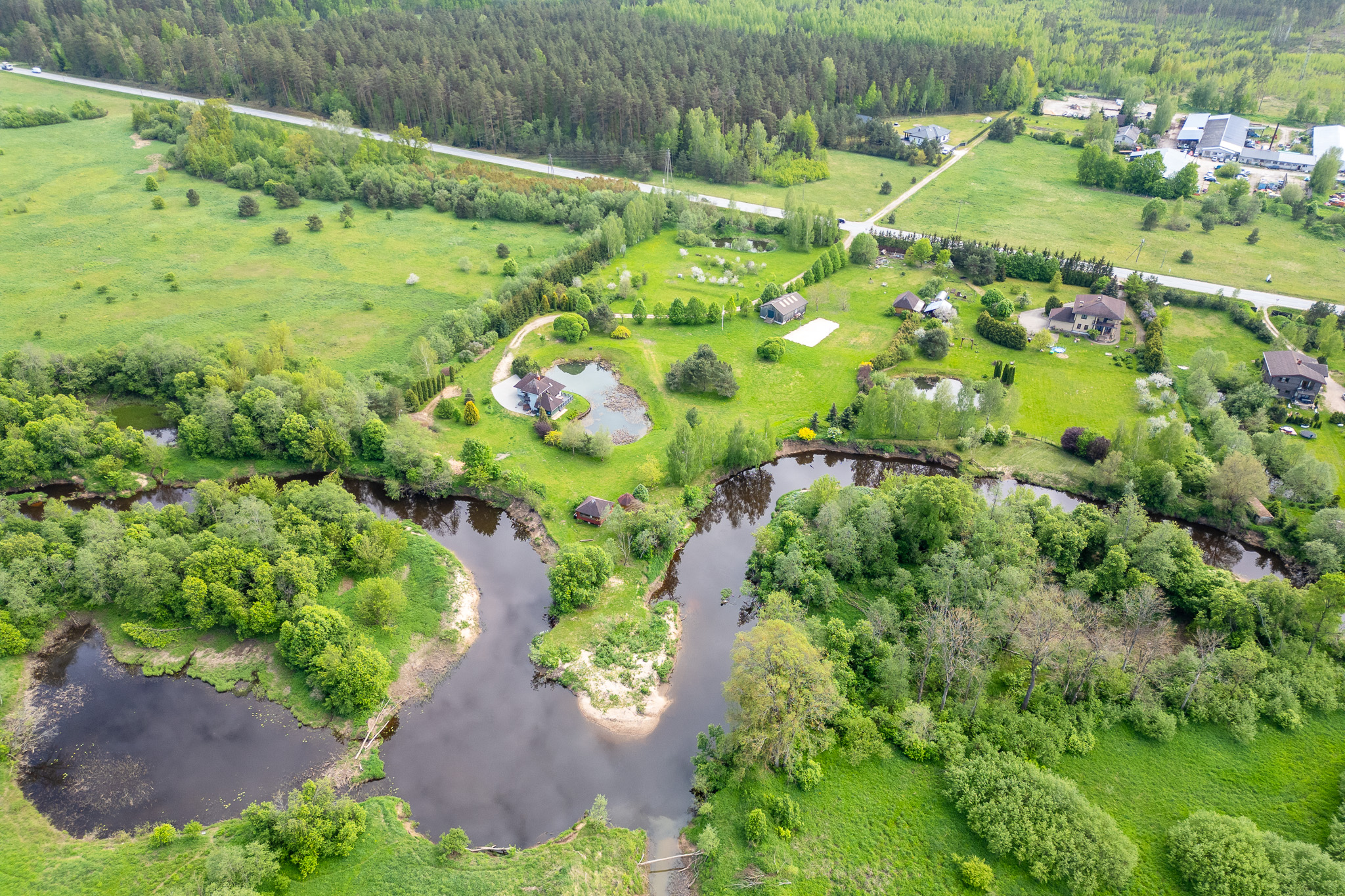 Ainavisks drona skats uz privātmājām, upes līkumiem un zaļu mežu. Kvalitatīvas nekustamā īpašuma fotogrāfijas.