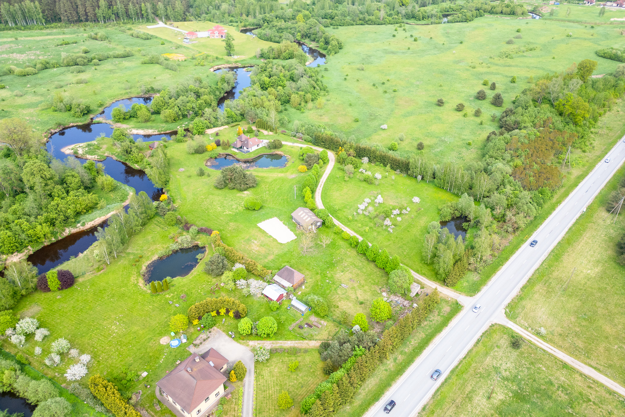 Ceļa krustojums un privātmājas piepilsētā, uzņemtas ar dronu. Nekustamā īpašuma fotogrāfijas.