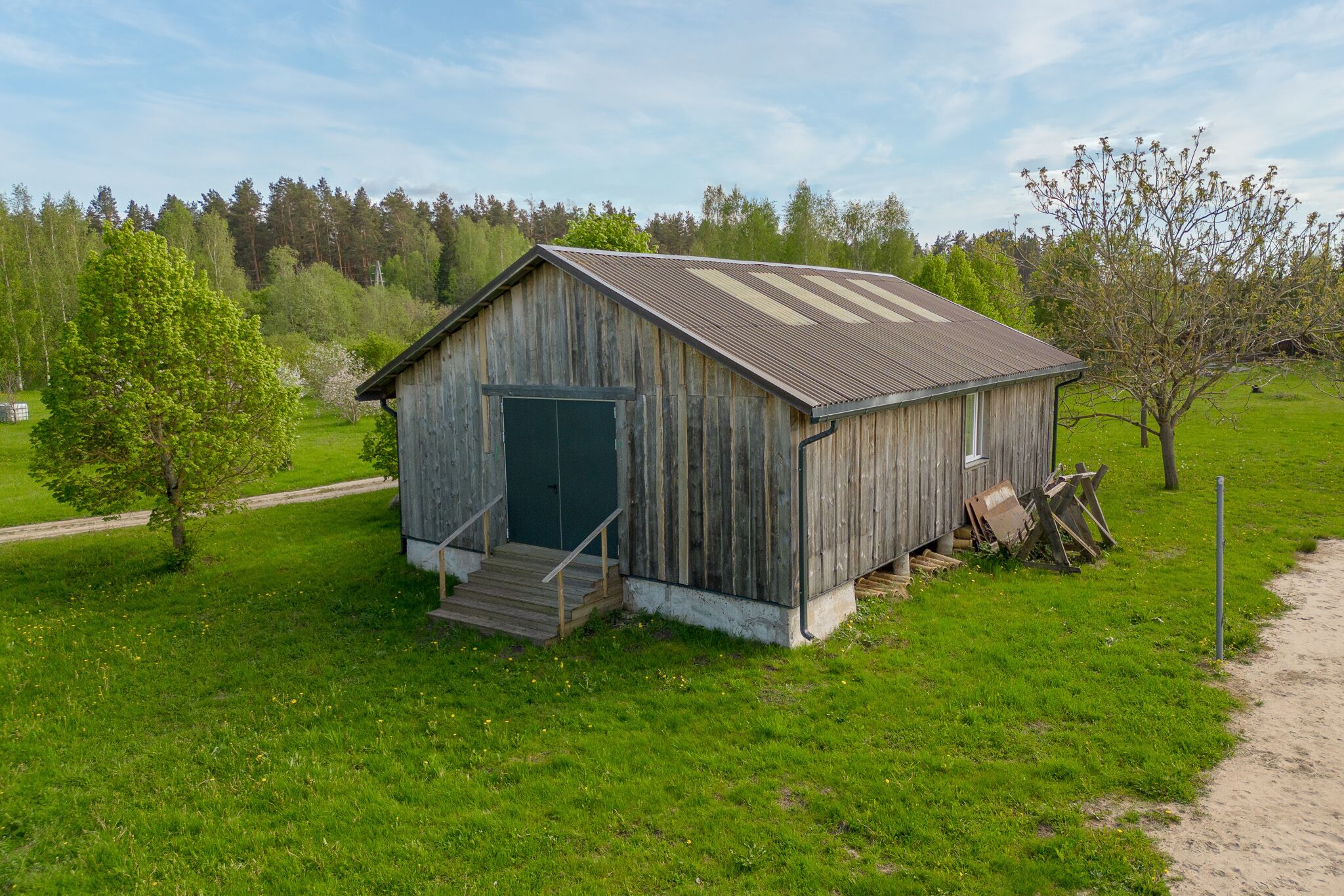 Kvalitatīva lauku īpašuma fotogrāfija: Koka saimniecības ēka ar zaļu mauriņu – drona fotogrāfijas un foto