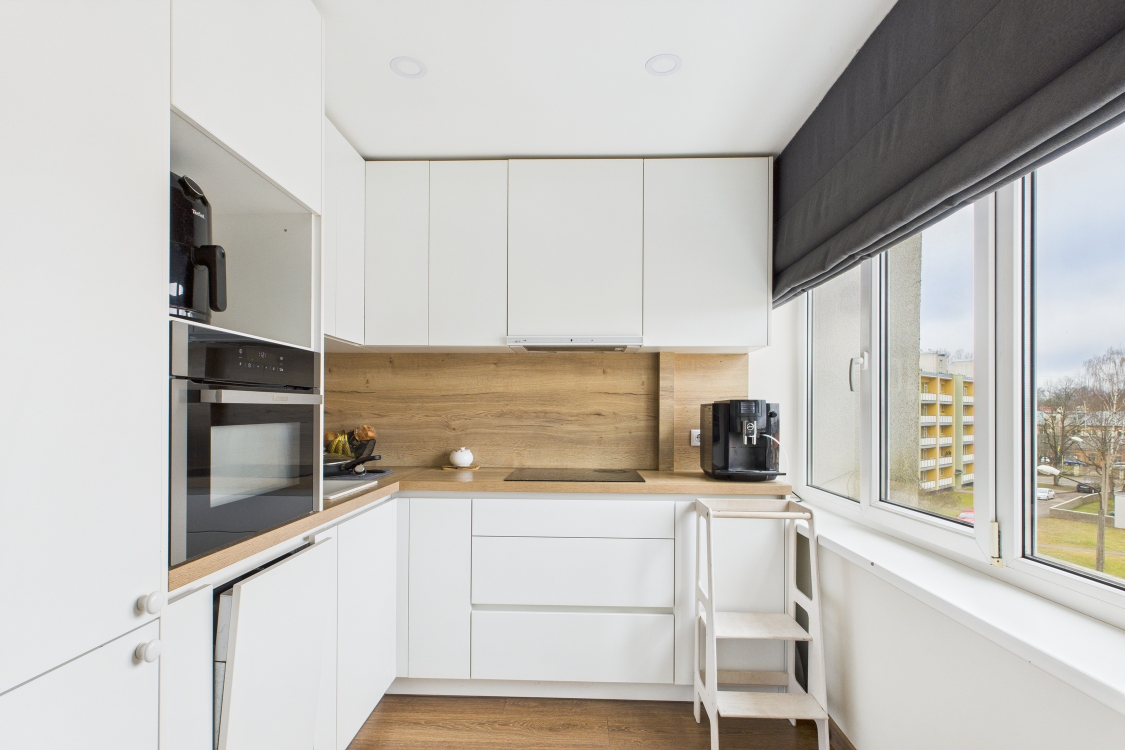 Kvalitatīva interjera fotogrāfija: Mūsdienīga virtuve ar baltām fasādēm un dabīgu apgaismojumu – nekustamā īpašuma fotogrāfijas