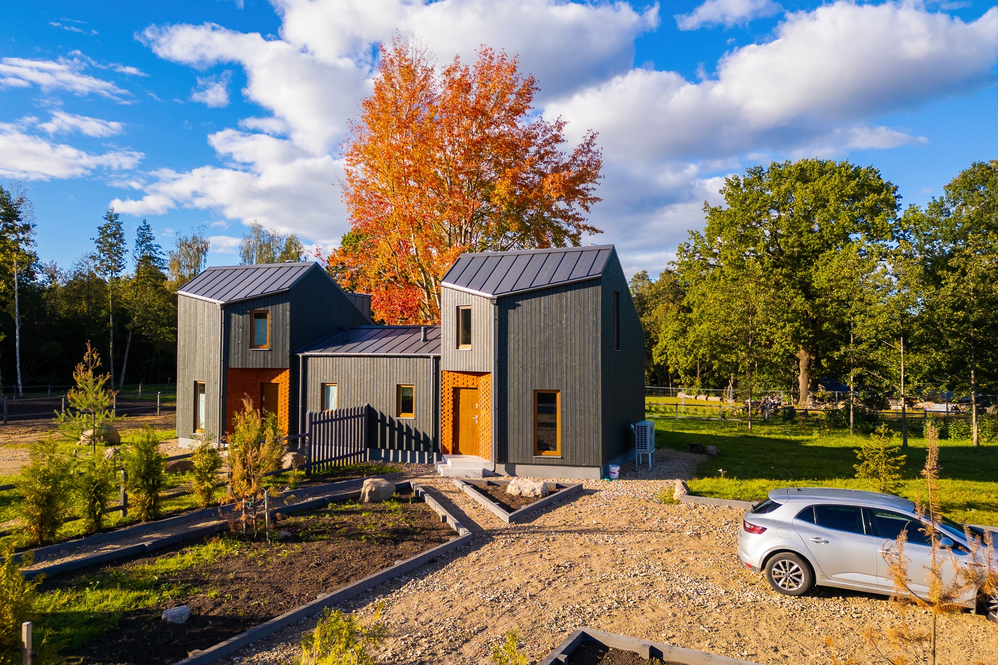 Kvalitatīva mājas fotogrāfija: Mūsdienīgas moduļu mājas ar tumšu apdari un rudens kokiem – drona fotogrāfijas un foto