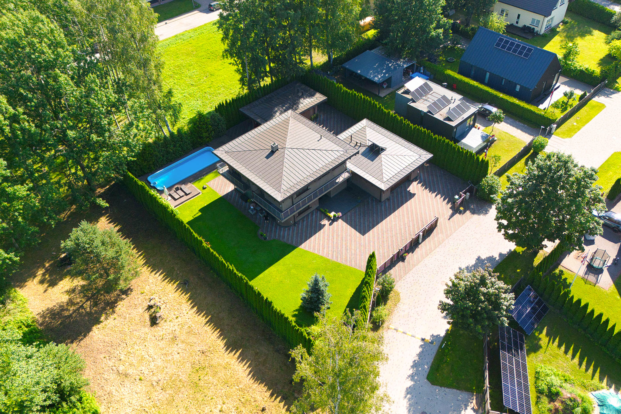 Kvalitatīva nekustamā īpašuma fotogrāfija ar dronu: Moderna māja ar baseinu un koptu teritoriju