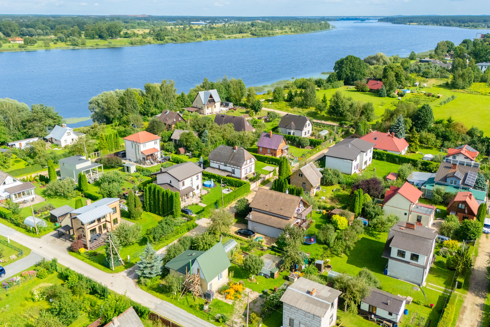 Kvalitatīva nekustamā īpašuma fotogrāfija ar dronu: Privātmāju apbūve pie upes Rīgas reģions