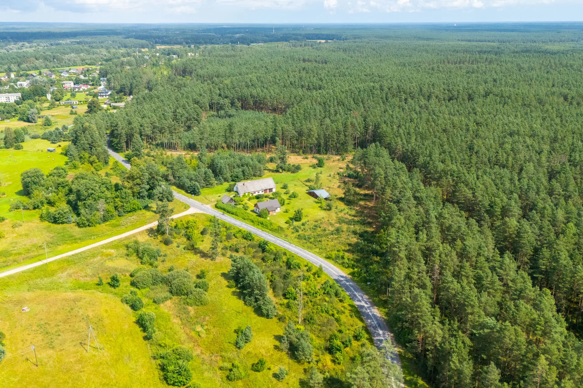 Ainavisks drona skats: Zemes gabali ar ceļu un mežu nekustamā īpašuma fotogrāfija