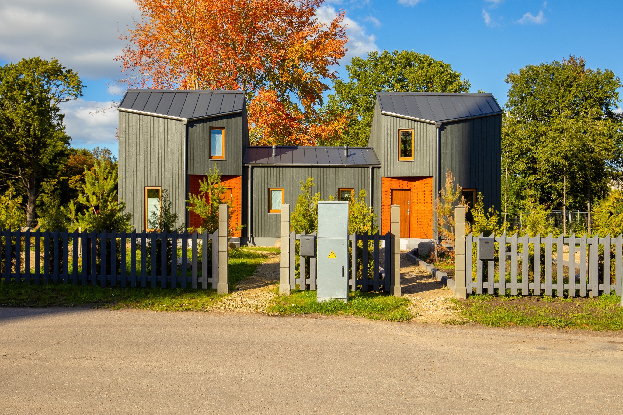 Kvalitatīva mājas fotogrāfija: Mūsdienīgas moduļu mājas ar tumšu apdari un oranžām durvīm – drona fotogrāfijas un foto