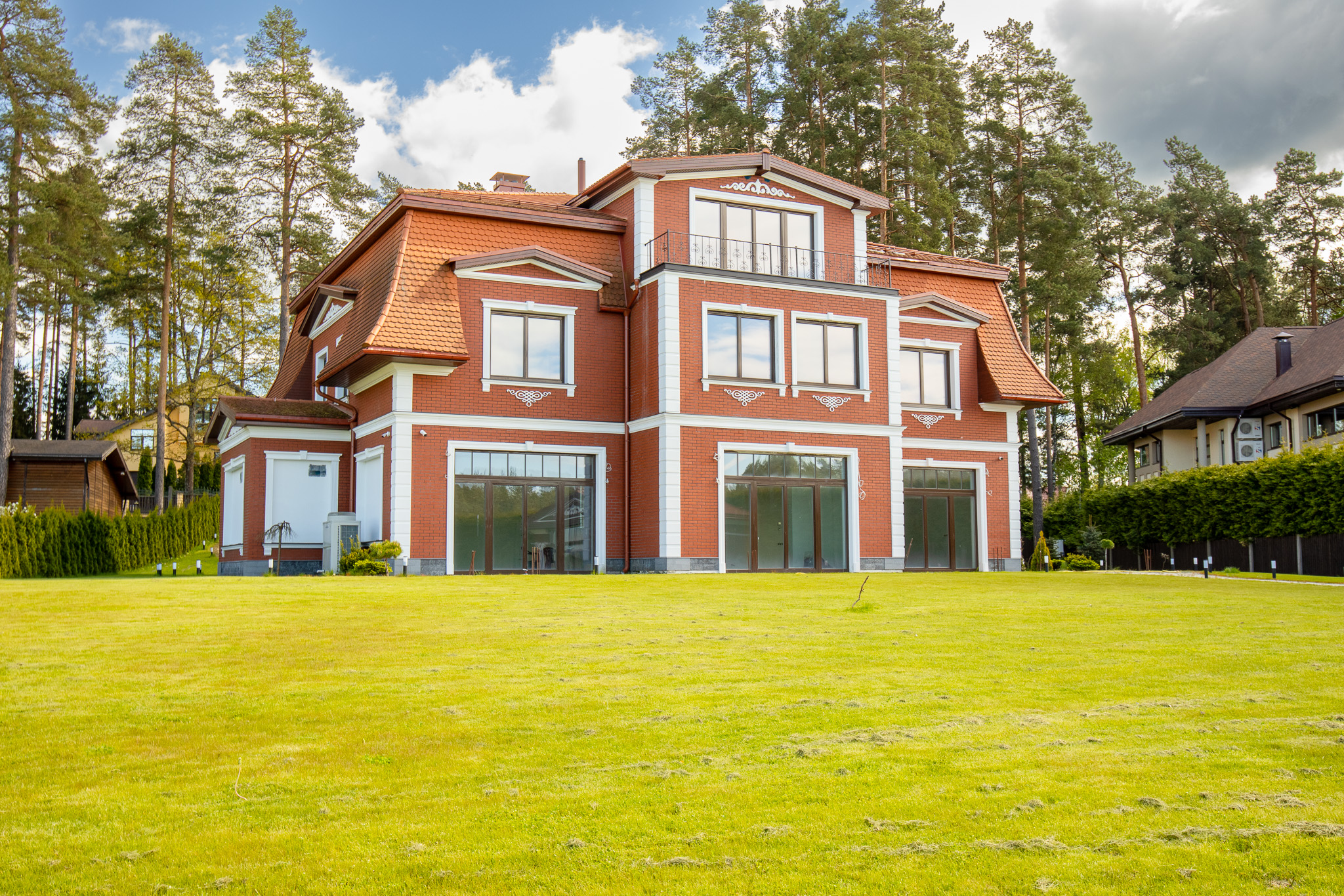 Kvalitatīva mājas fotogrāfija: Grezna divstāvu māja ar sarkanu akcentu un plašu mauriņu – drona fotogrāfijas un foto